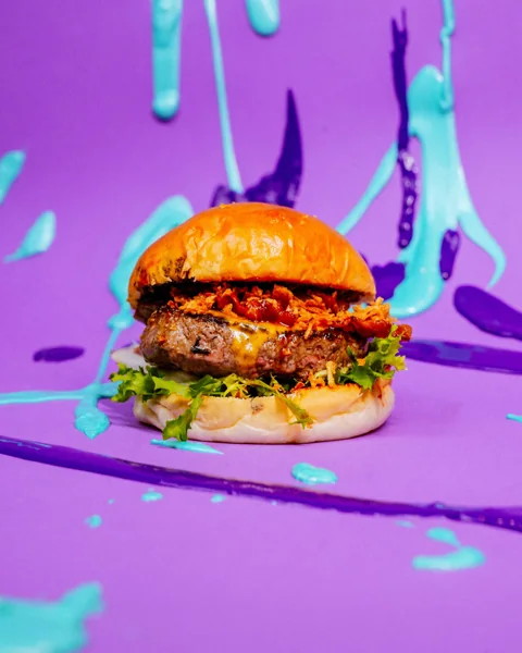 Burger su sfondo viola con schizzi di colore